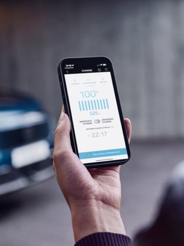 Mulher com smartphone em frente ao PEUGEOT E-3008 Dual Motor